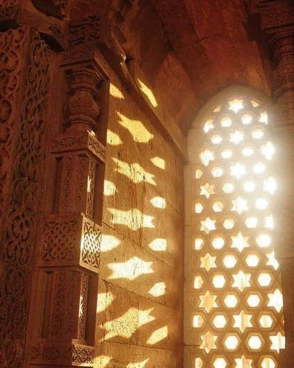 Sunlight streaming through ornate lattice window casting patterned shadows on carved stone wall